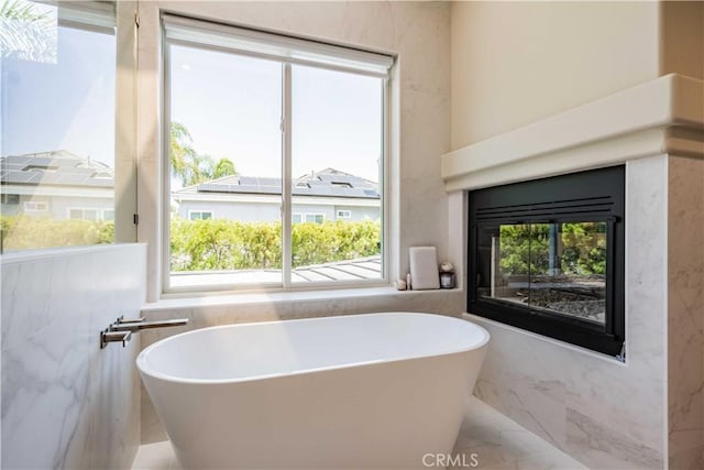 bathroom featuring a bathing tub, tile walls, and a healthy amount of sunlight