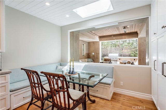 dining area featuring wood ceiling, a skylight, and light hardwood / wood-style floors