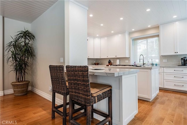 kitchen featuring white cabinets, a breakfast bar, and light hardwood / wood-style flooring