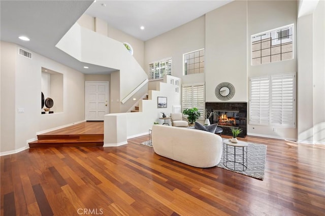 living room featuring hardwood / wood-style flooring, a high ceiling, and a fireplace