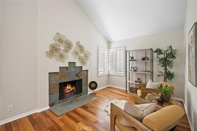 living area with hardwood / wood-style flooring, high vaulted ceiling, and a tile fireplace