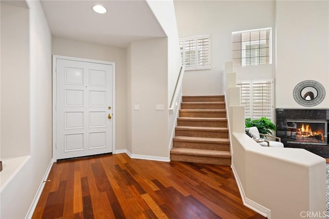 stairs featuring hardwood / wood-style floors, a premium fireplace, and a healthy amount of sunlight