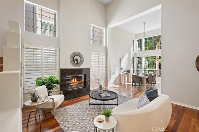 living room with hardwood / wood-style flooring, a premium fireplace, and a high ceiling