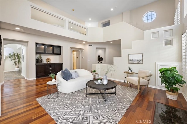 living room featuring a towering ceiling and dark hardwood / wood-style flooring