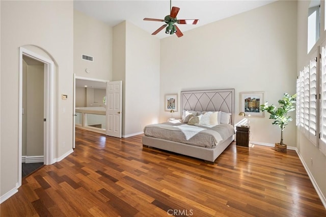 bedroom with dark wood-type flooring, ceiling fan, and a towering ceiling