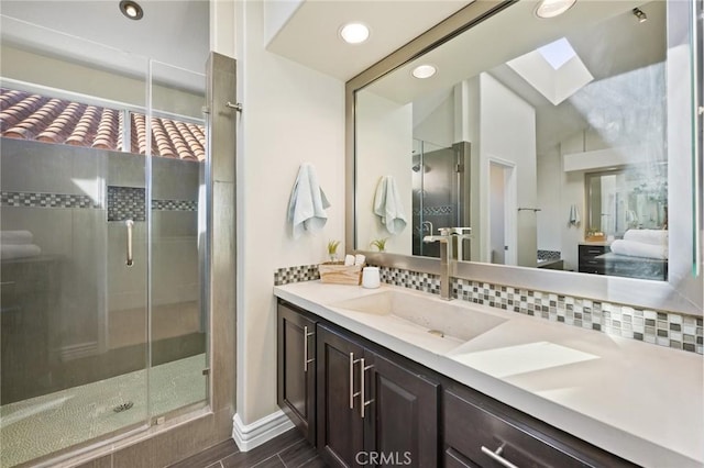 bathroom featuring vanity, backsplash, a skylight, and walk in shower