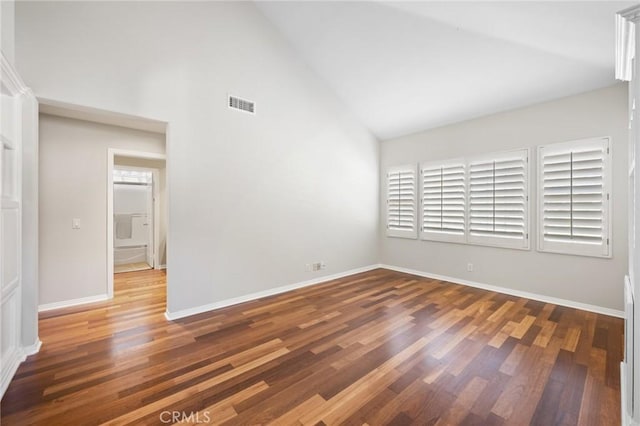 unfurnished room with dark wood-type flooring and high vaulted ceiling