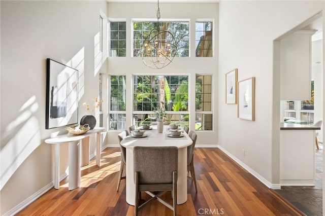 dining room with dark hardwood / wood-style flooring, a notable chandelier, and a high ceiling