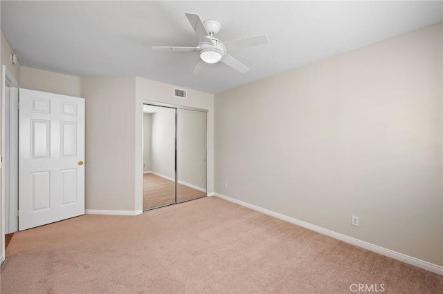 unfurnished bedroom featuring light carpet, a closet, and ceiling fan