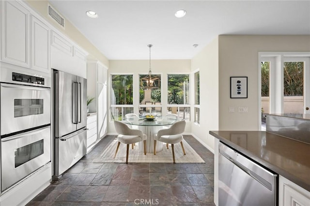 kitchen featuring appliances with stainless steel finishes, pendant lighting, a wealth of natural light, and white cabinets