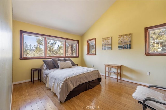 bedroom featuring light hardwood / wood-style floors and high vaulted ceiling