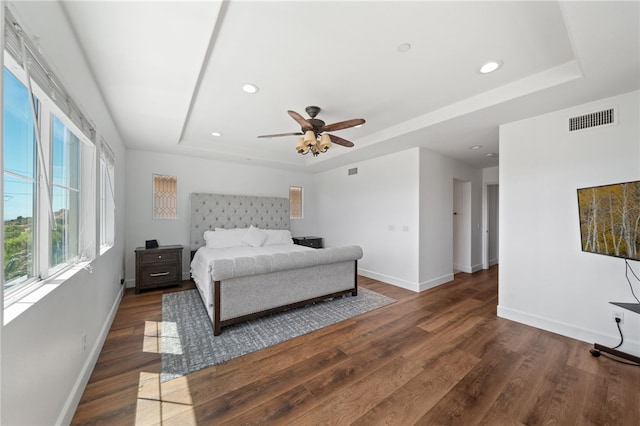 bedroom featuring ceiling fan, dark hardwood / wood-style floors, and a tray ceiling