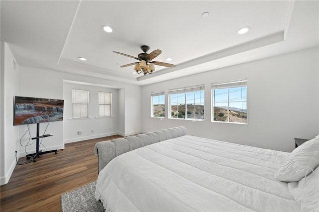 bedroom with a raised ceiling, ceiling fan, and dark wood-type flooring