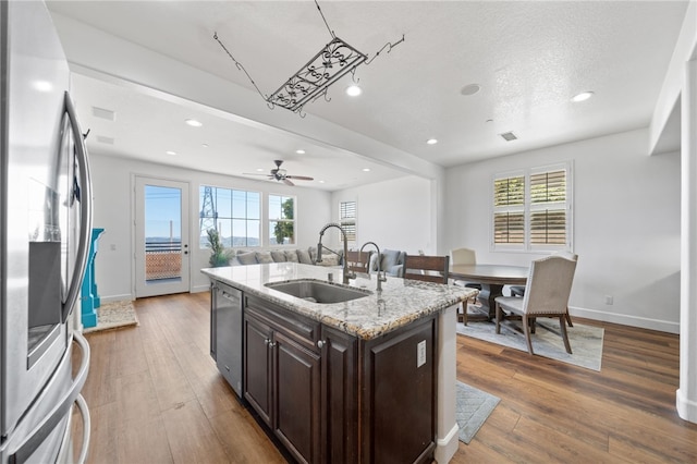 kitchen featuring stainless steel appliances, a healthy amount of sunlight, a kitchen island with sink, dark wood-type flooring, and sink