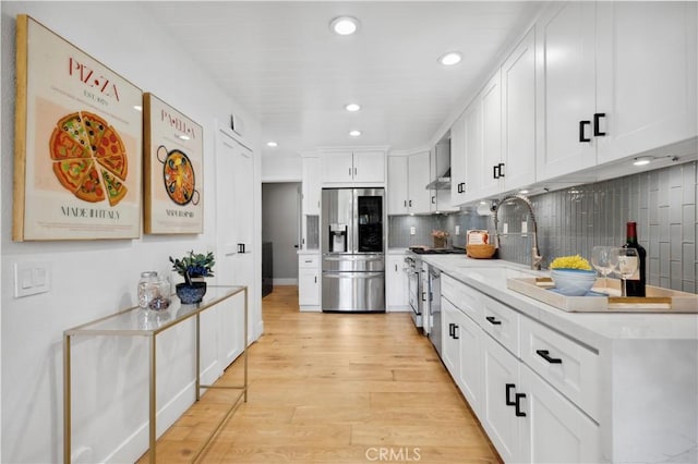 kitchen with light countertops, appliances with stainless steel finishes, white cabinetry, a sink, and light wood-type flooring