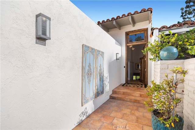 view of exterior entry featuring a tile roof and stucco siding