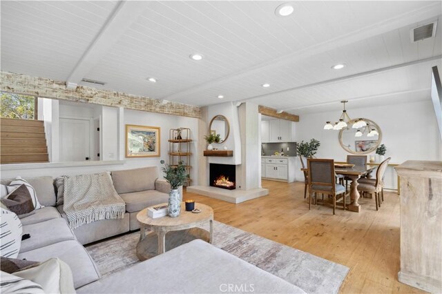 living room featuring beamed ceiling, light hardwood / wood-style floors, wood ceiling, and an inviting chandelier