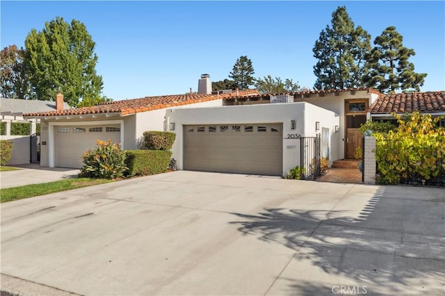 mediterranean / spanish home with a tile roof, an attached garage, and stucco siding