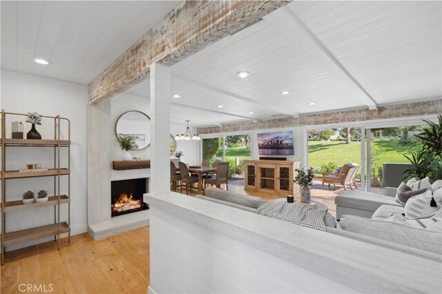 living room with a large fireplace, light hardwood / wood-style floors, and wood ceiling