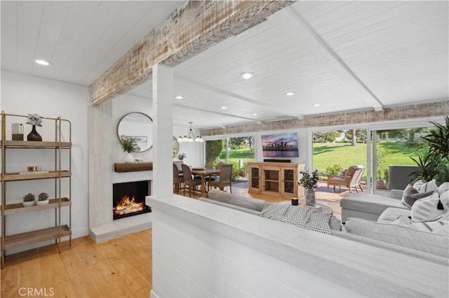 living area featuring recessed lighting, beam ceiling, a fireplace, and wood finished floors