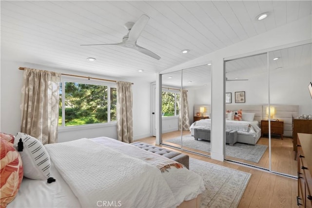 bedroom with light wood-style flooring, ceiling fan, two closets, and recessed lighting