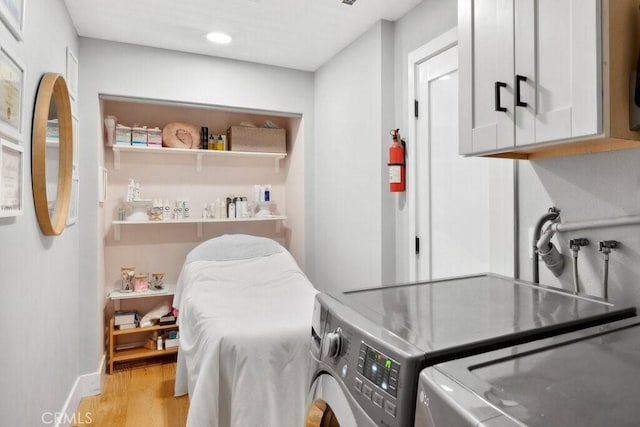 laundry area with cabinets, independent washer and dryer, and light hardwood / wood-style flooring