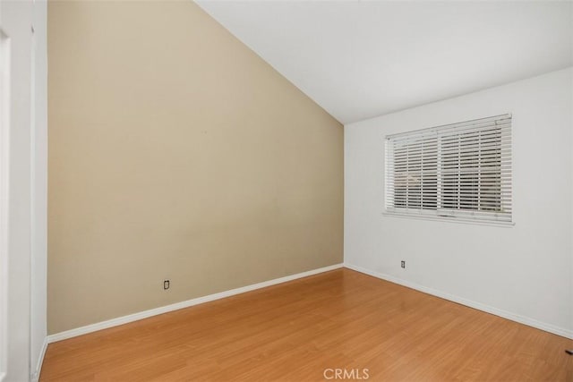 spare room with hardwood / wood-style floors and vaulted ceiling