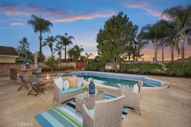 pool at dusk featuring a patio and an outdoor fire pit