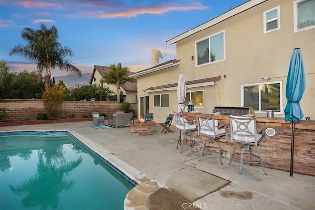 back house at dusk with a fenced in pool, an outdoor fire pit, and a patio