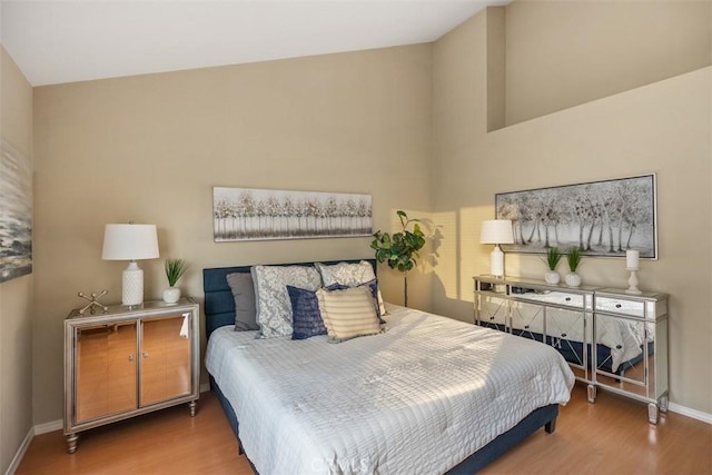 bedroom with wood-type flooring and vaulted ceiling