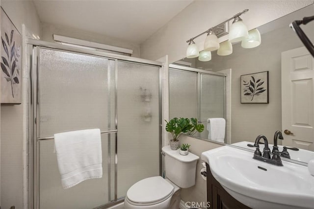 bathroom featuring vanity, toilet, and a shower with shower door