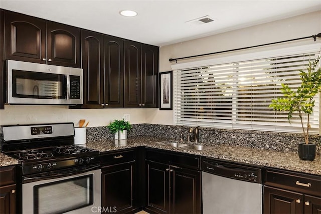 kitchen featuring light stone countertops, dark brown cabinets, stainless steel appliances, and sink