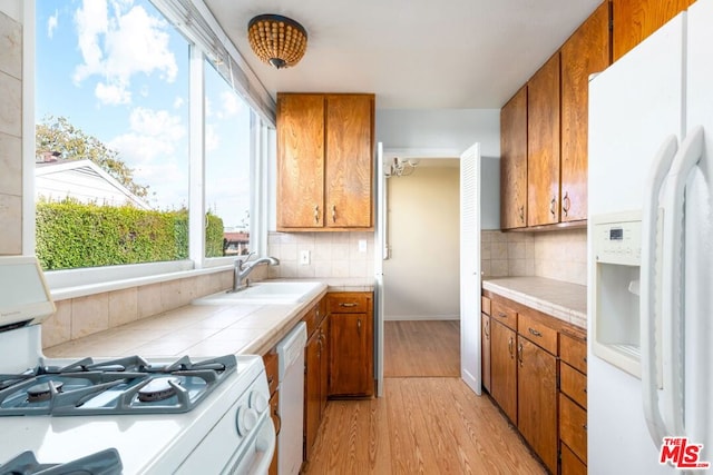 kitchen featuring white appliances, backsplash, an inviting chandelier, sink, and light hardwood / wood-style floors