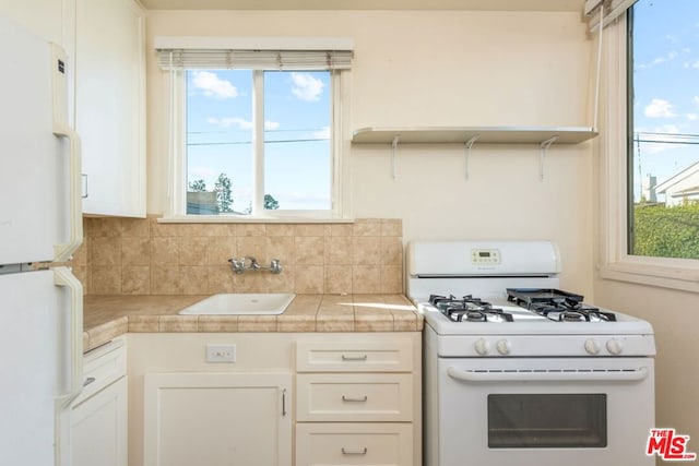 kitchen with plenty of natural light, sink, white cabinets, and white appliances