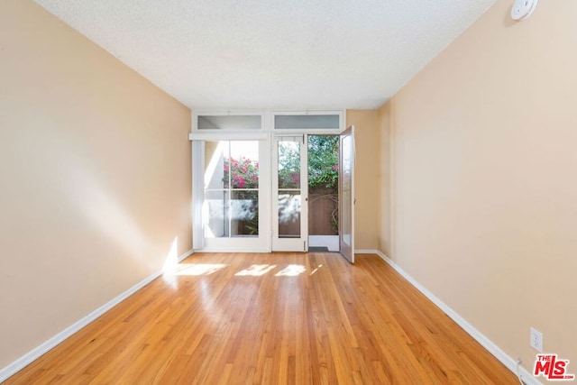 unfurnished room with light hardwood / wood-style floors and a textured ceiling