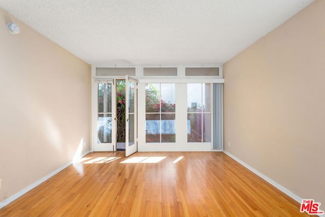 empty room with a textured ceiling and light hardwood / wood-style floors