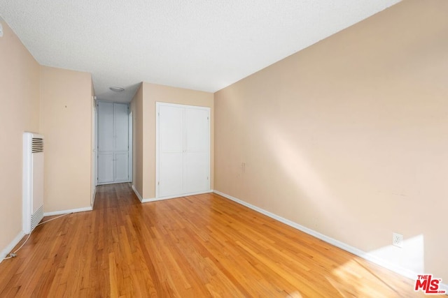 spare room featuring light hardwood / wood-style flooring and a textured ceiling