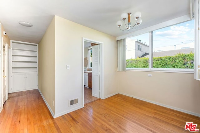 unfurnished dining area featuring a chandelier and light hardwood / wood-style floors