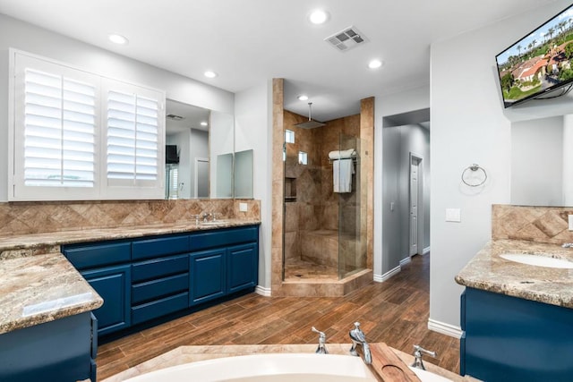 bathroom featuring vanity, wood-type flooring, and tiled shower