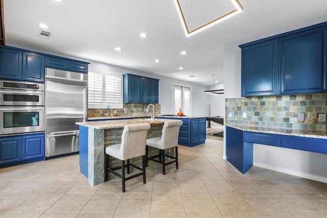 kitchen featuring a center island with sink, a breakfast bar, blue cabinets, and stainless steel appliances