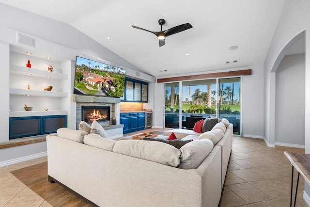 living room with built in shelves, ceiling fan, beverage cooler, vaulted ceiling, and light tile patterned floors