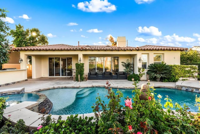 rear view of house with a patio and a pool with hot tub