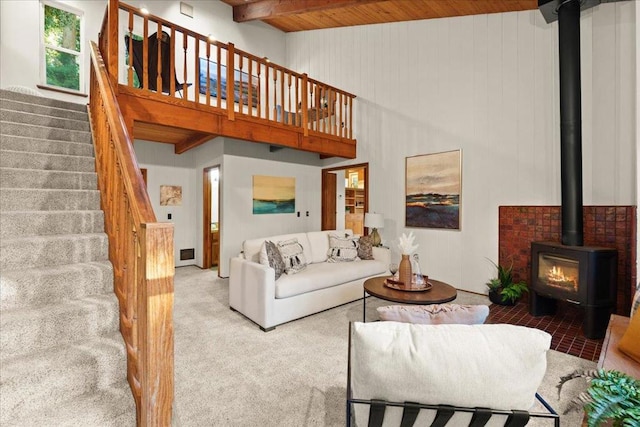 carpeted living room featuring a towering ceiling and a wood stove