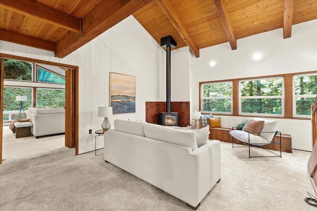 living room with beam ceiling, wooden ceiling, a wood stove, and light colored carpet