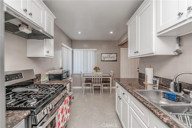 kitchen featuring sink, light tile patterned floors, dark stone counters, white cabinets, and appliances with stainless steel finishes