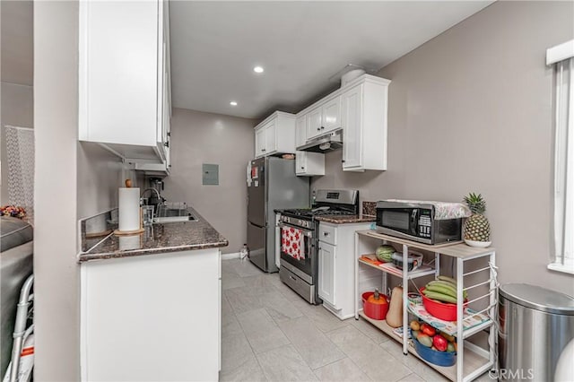 kitchen featuring white cabinets, appliances with stainless steel finishes, dark stone countertops, and sink