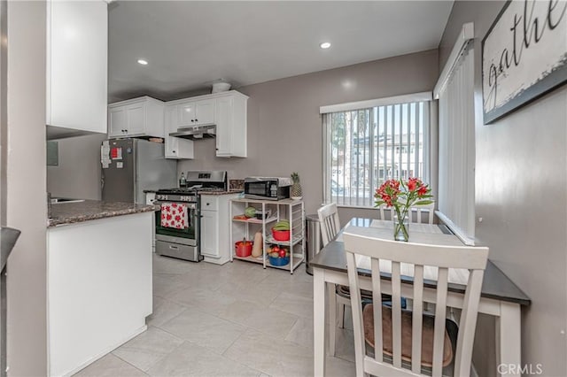 kitchen with light tile patterned floors, white cabinetry, appliances with stainless steel finishes, and dark stone counters