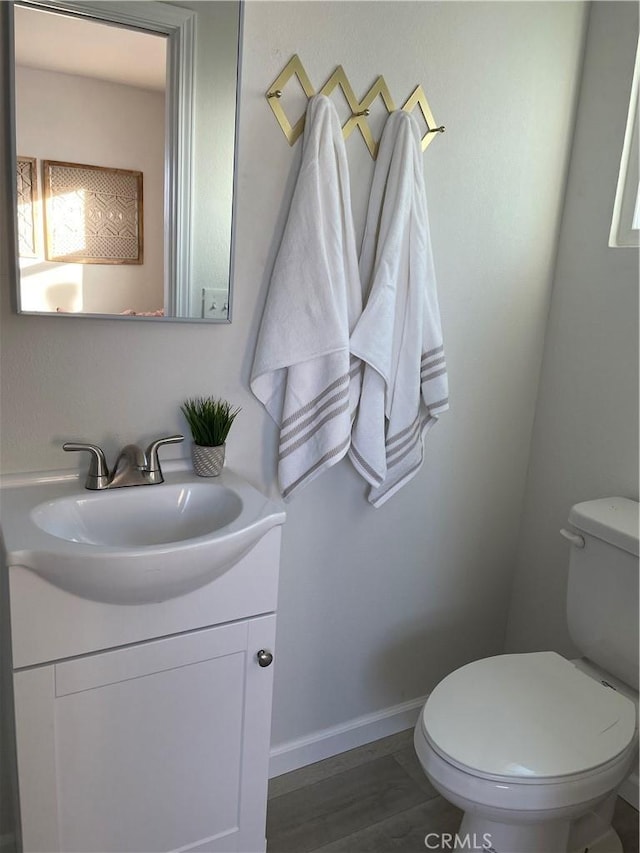 bathroom with toilet, vanity, and hardwood / wood-style flooring