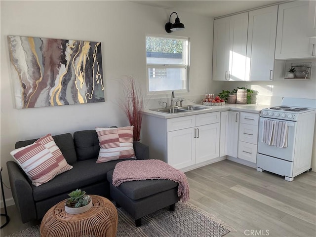 kitchen featuring white cabinets, stove, light wood-type flooring, and sink