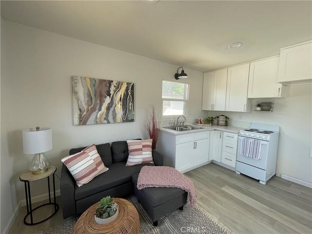 kitchen with white cabinets, white range, light wood-type flooring, and sink